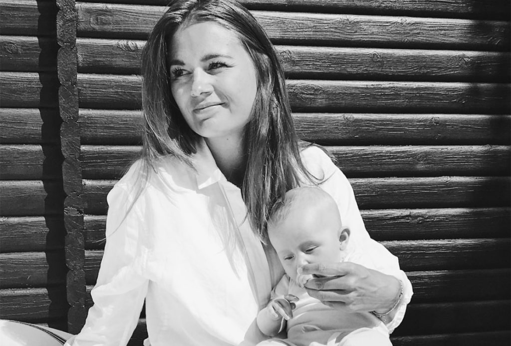 Mette Østergaard i hvid skjorte med baby på skødet