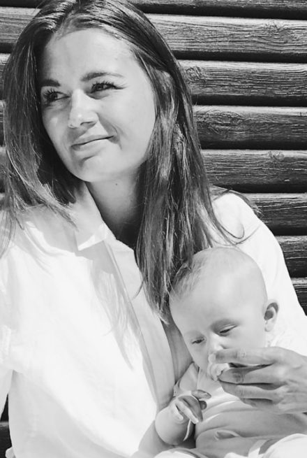 Mette Østergaard i hvid skjorte med baby på skødet