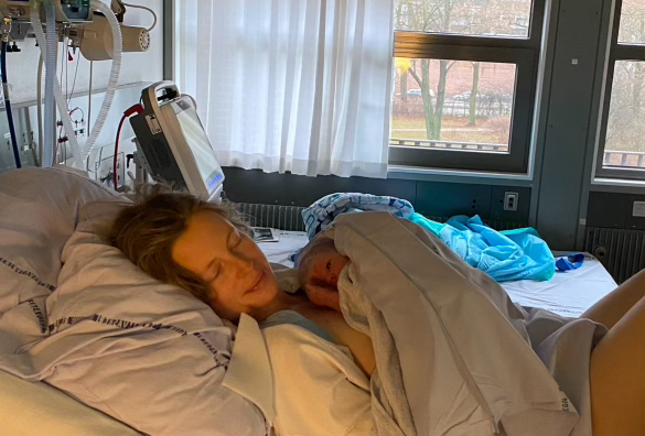 Mor på hospitalsseng lige efter fødsel med nyfødt baby i armene