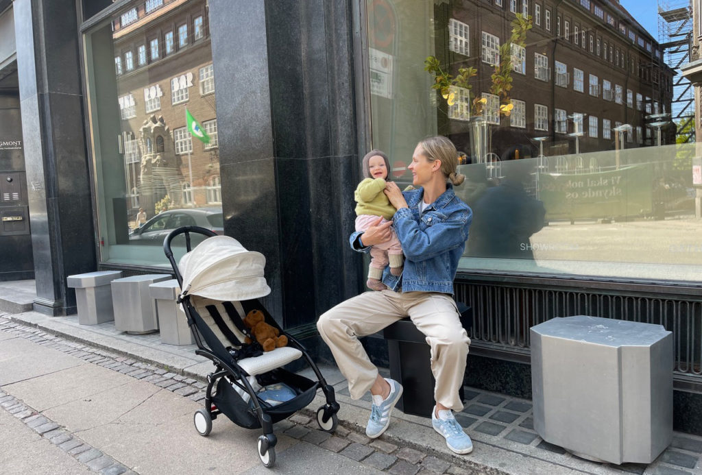 Bea Fagerholt sidder på bænk med baby og klapvogn