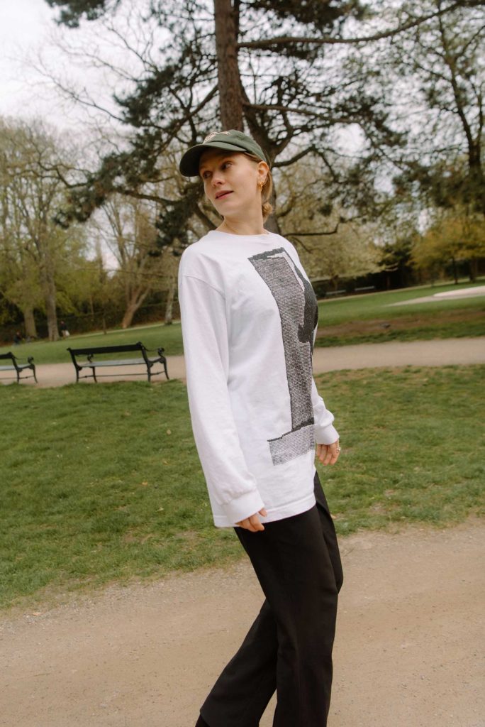 Emma Holten i hvid t-shirt, kasket og sorte bukser i park