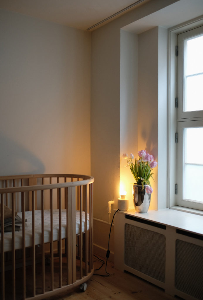 Babyseng i børneværelse ved siden af vindueskarm med blomsterbuket