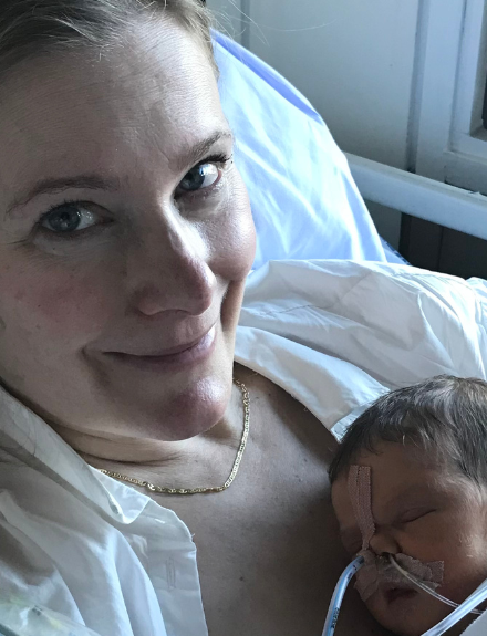 Kvinde med nyfødt baby på hospital. Hospitalstøj