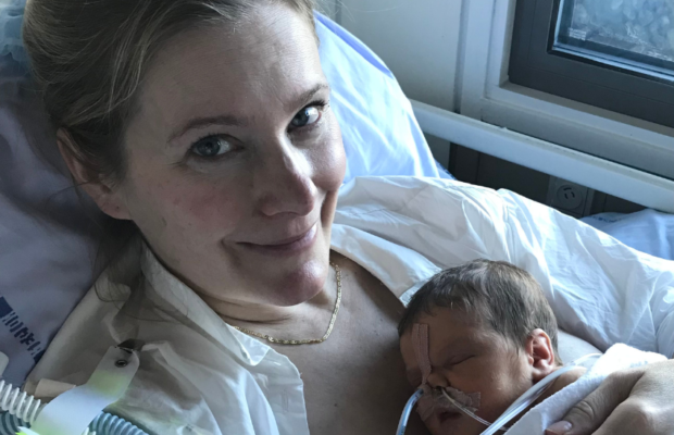 Kvinde med nyfødt baby på hospital. Hospitalstøj