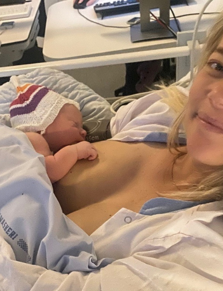Kvinde der lige har født ved kejsersnit på et hospital med nyfødt baby smiler