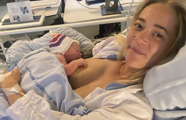 Kvinde der lige har født ved kejsersnit på et hospital med nyfødt baby smiler
