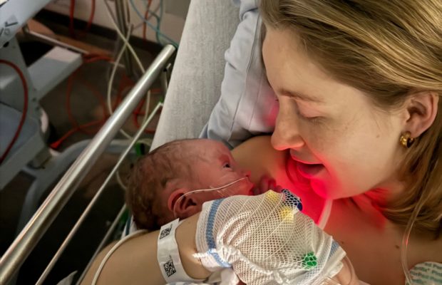 Kvinde i hospitalsseng med nyfødt baby i armene