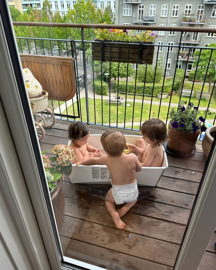 tre børn der leger i en bajle på altanen