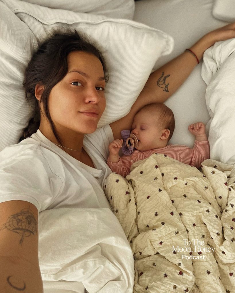 Kvinde liggende i seng med lille baby