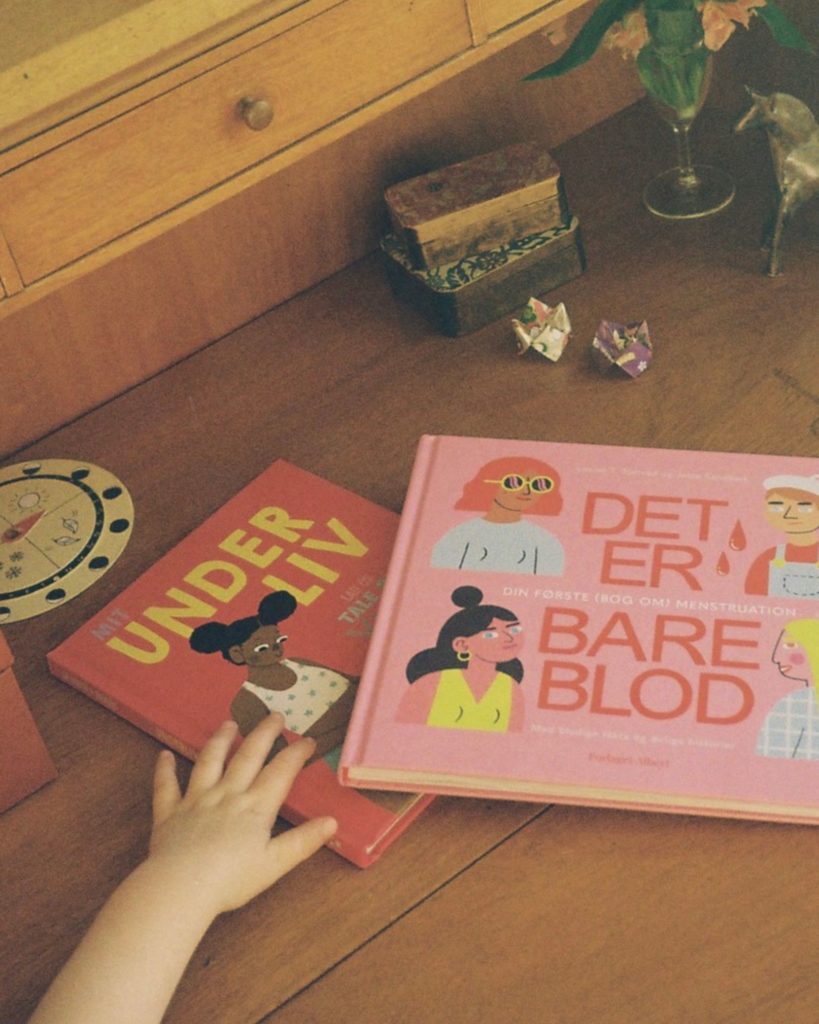 Barnehånd der rækker ud efter bøger på bordet