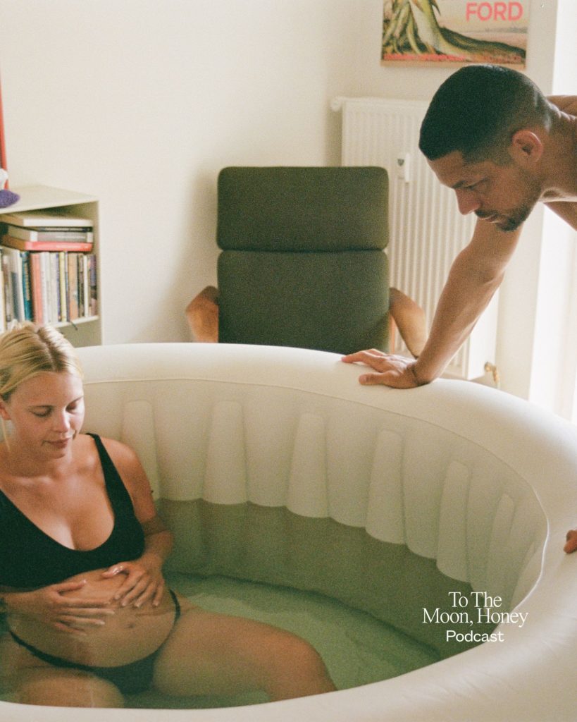 Fødende kvinde i badekar med sin mand på sidelinjen