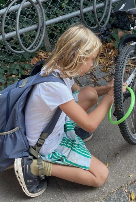 barn med skoletasken og en cykel - første skoledag