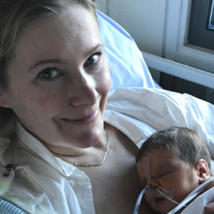 Kvinde med nyfødt baby på hospital. Hospitalstøj