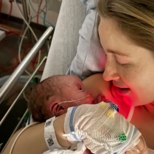 Kvinde i hospitalsseng med nyfødt baby i armene