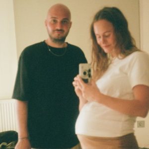 Mand og gravid kvinde poserer sammen foran spejl