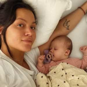 Kvinde liggende i seng med lille ny baby